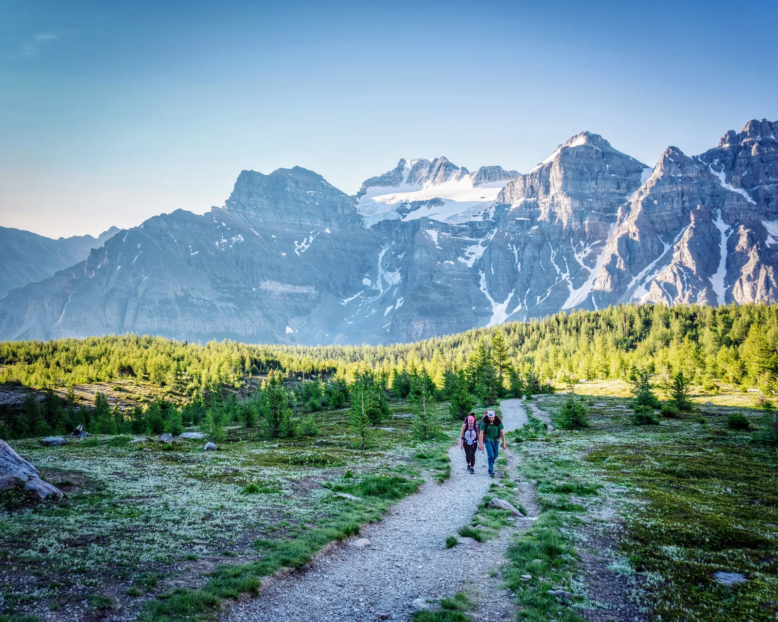 Pair of people with well equipped packs emerging from the larches of Larch Valley